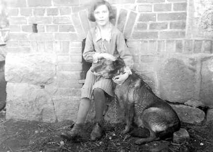 050 0010 Charlotte Gudde im Alter von 12 Jahren mit ihrer heissgeliebten Wolfshuendin Ziema vor der in den Schweinestall eingebauten Hundehuette